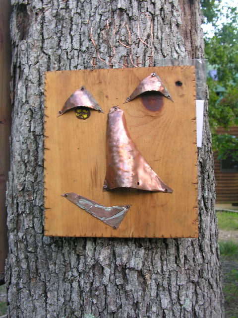 Minimal copper face mounted on a square natural wood panel