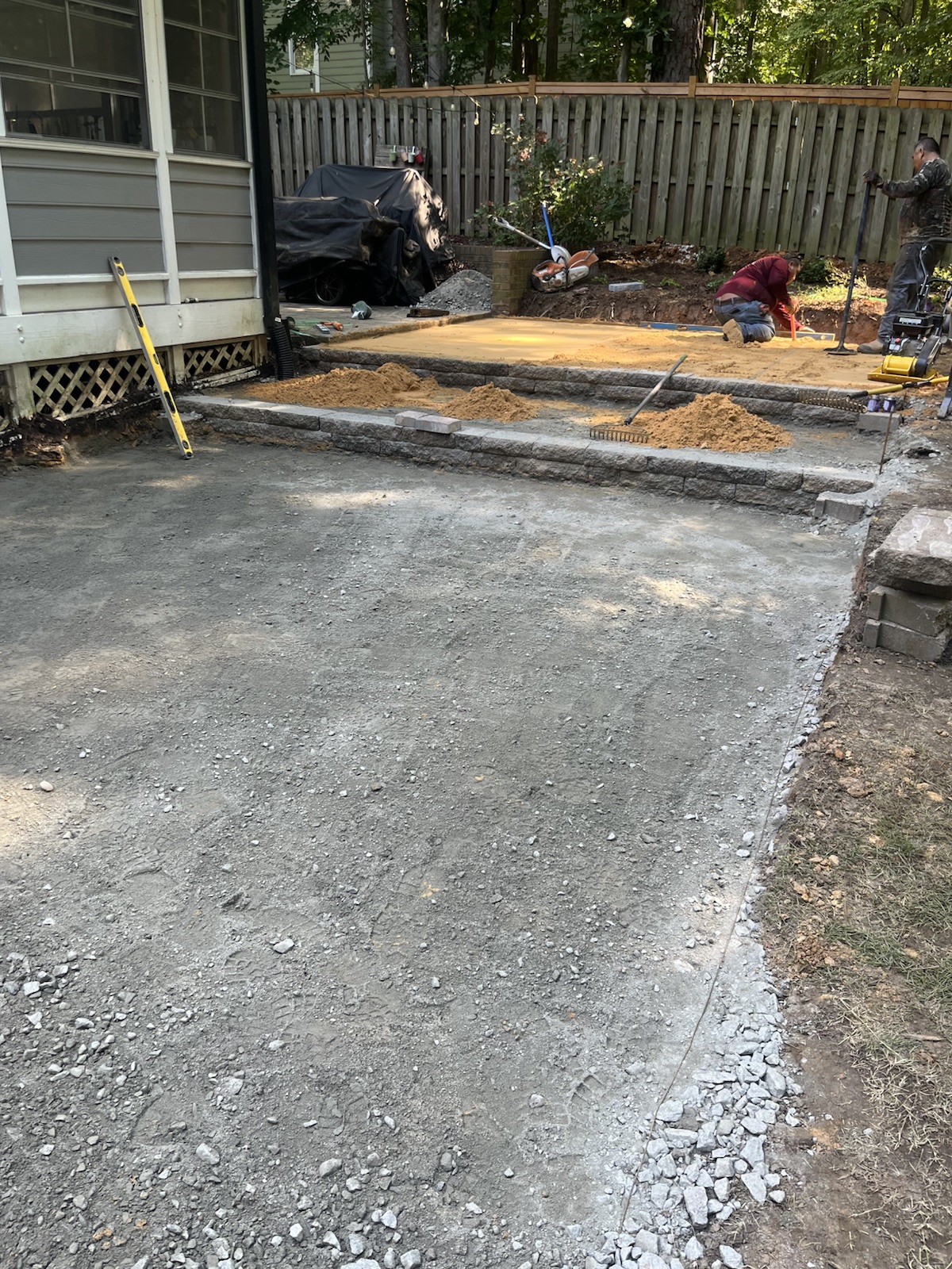 Prepared aggregate base, bedding layer and low wall during a residential patio installation