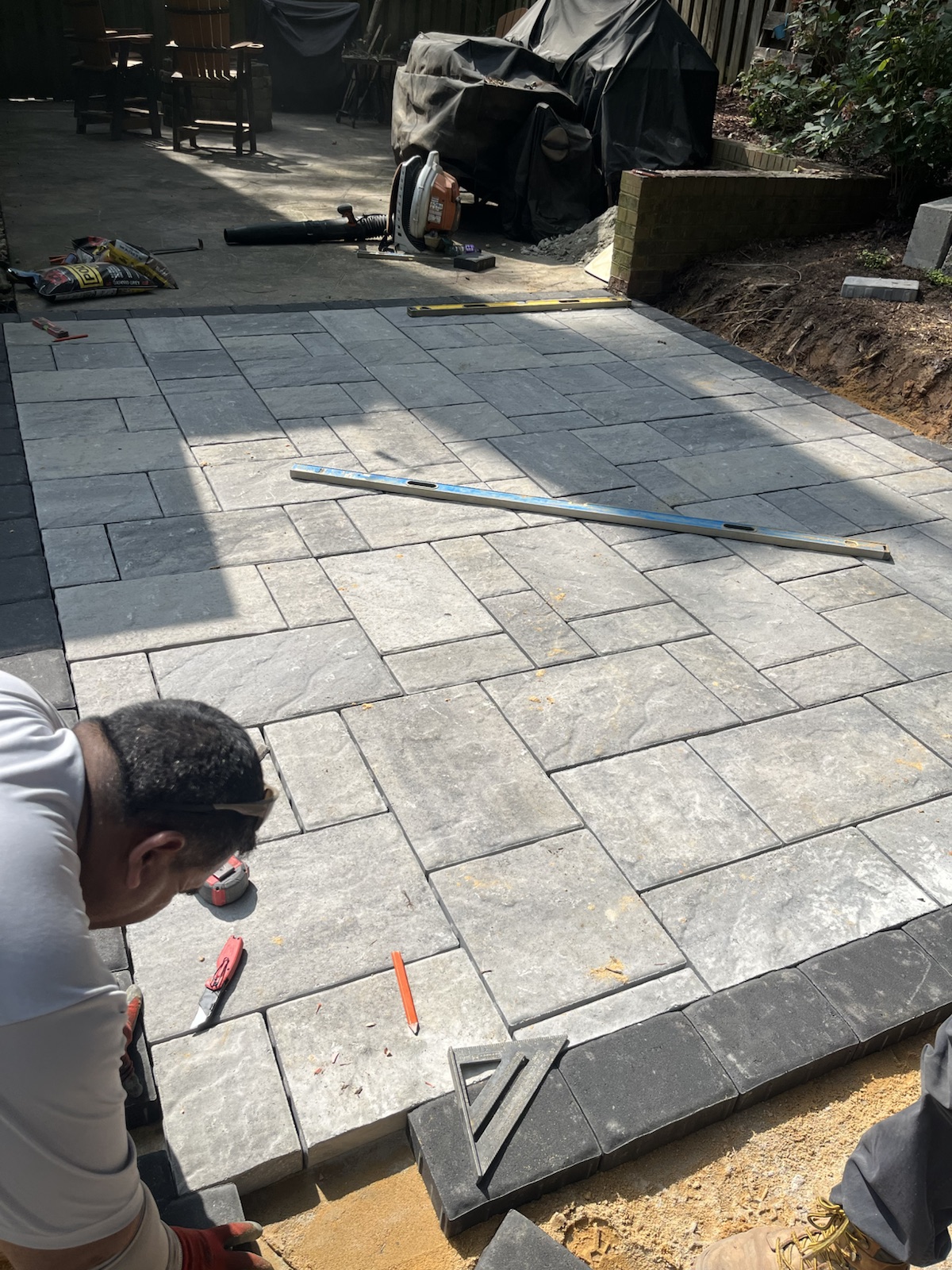 Landscape crew setting gray pavers on an in-progress residential patio